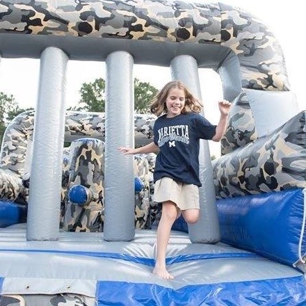 Student in Marietta t-shirt smiling and jumping out of bounce house